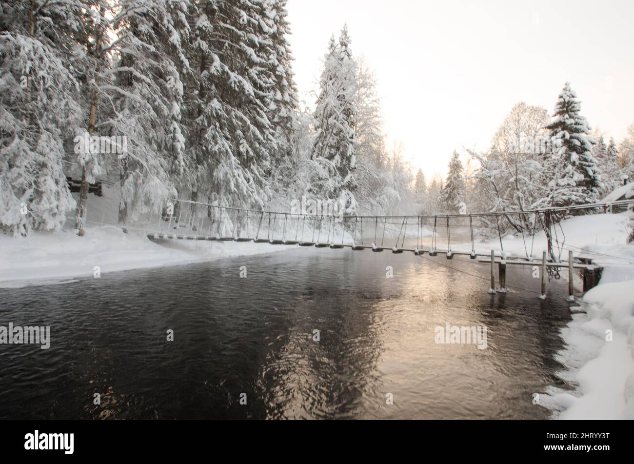 Holzbrücke über einen Waldfluss. Frostfreie Gewässer. Einfrieren. Winterlandschaft im Wald Stockfoto