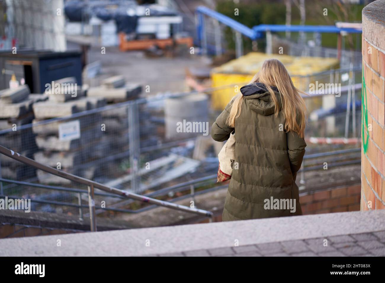 Stuttgart, 06. Januar 2022: Junge Frau in Winterkleidung geht die Stufen hinunter. Baustellenbahnprojekt Stuttgart 21. Stockfoto