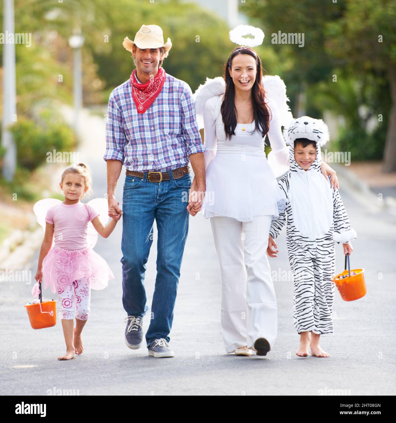 Diese Kollektion von Outfits ist unschlagbar. In voller Länge aufgenommen, wie eine Familie in ihren Halloween-Kostümen die Straße entlang läuft. Stockfoto