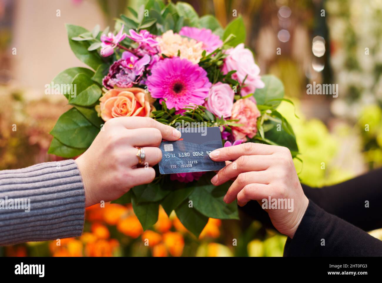 Beweisen, dass Sie Schönheit kaufen können. Kurzer Schuss einer Frau, die Blumen mit ihrer Kreditkarte von einem Floristen kauft. Stockfoto