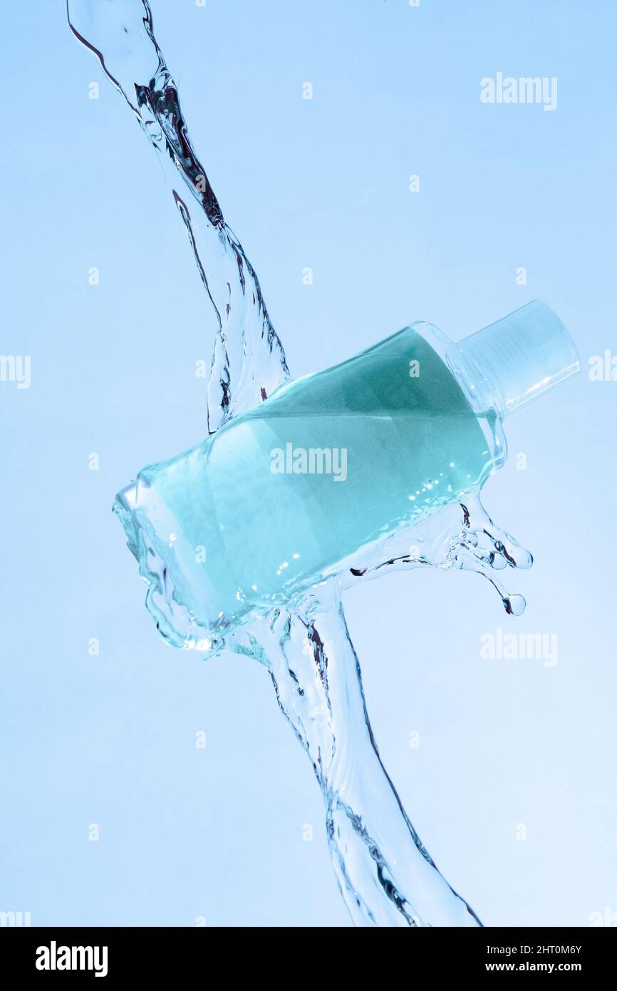 Vertikale Aufnahme eines blauen Beauty-Produkts unter fließendem Wasser auf blauem Hintergrund Stockfoto