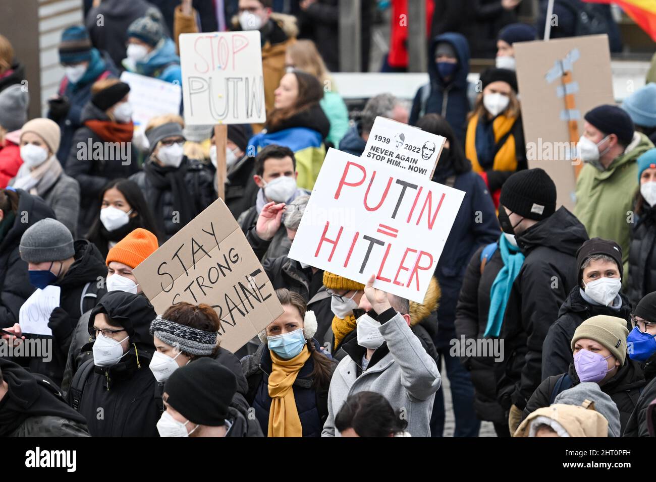 München, Deutschland. 26.. Februar 2022. Demonstranten halten Plakate mit den Aufschrift „Putin=Hitler“ und „bleibt stark in der Ukraine“ während einer Demonstration am Odeonsplatz gegen den russischen Angriff auf die Ukraine. Quelle: Tobias Hase/dpa/Alamy Live News Stockfoto