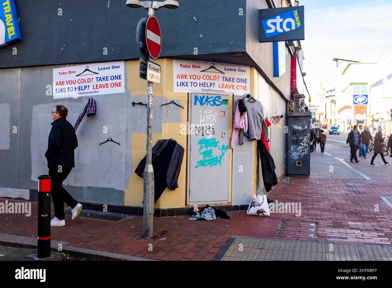 Brighton UK 26. February 2022 - die Menschen kommen an der Kleiderabgabestelle "Take One Leave One" in einem alten Reisegeschäft im Stadtzentrum von Brighton vorbei. Mitglieder der Öffentlichkeit werden gebeten, denen zu helfen, die im Winter kalt sind oder auf der Straße leben, indem sie unerwünschte Kleidung auf den Kleiderbügeln zur Verfügung gestellt : Credit Simon Dack / Alamy Live News Stockfoto