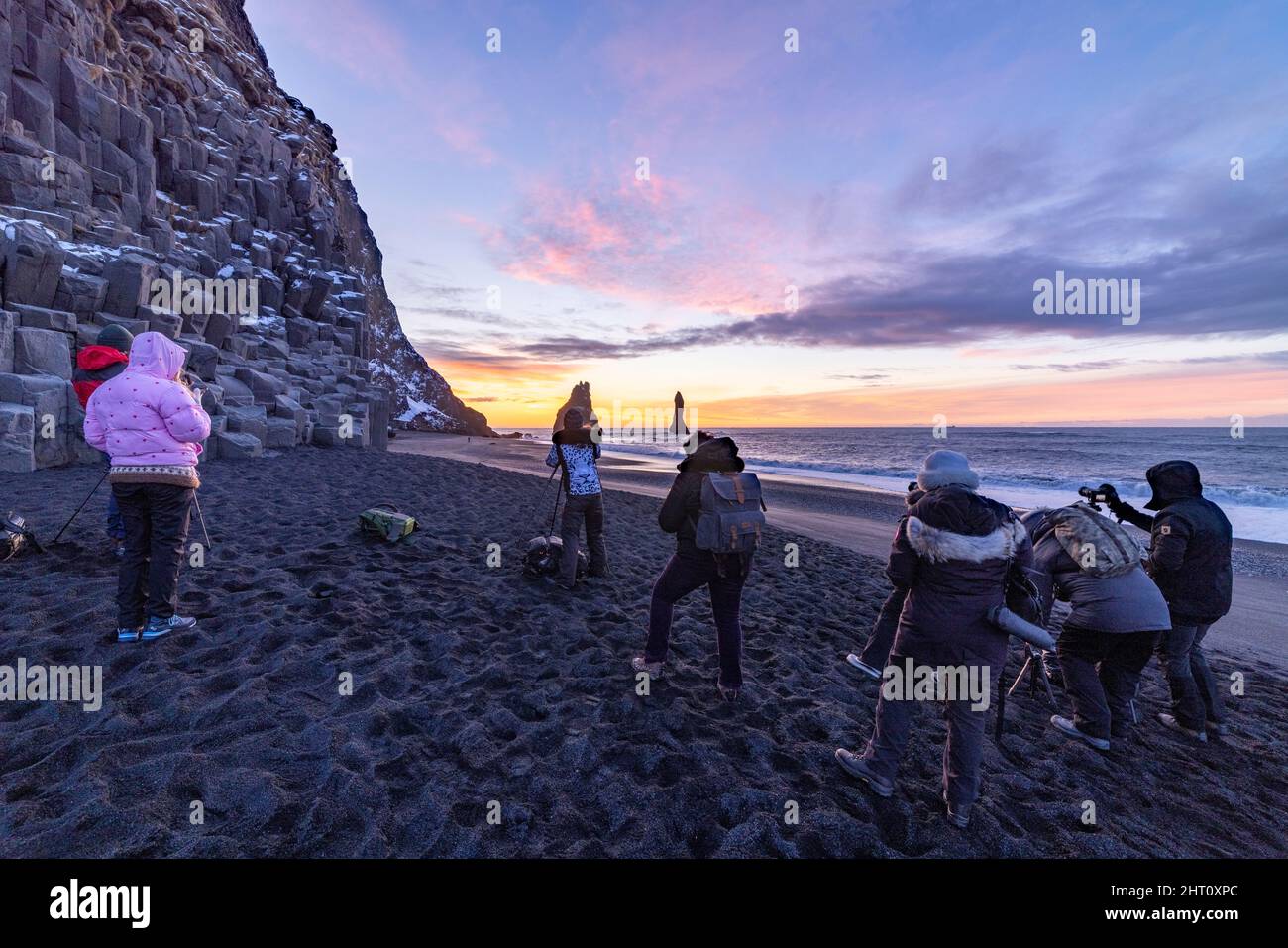 Fotografen, die den dramatischen Sonnenaufgang über dem Reynisfjara Black Sand Beach in der Nähe des Dorfes Vík i Myrdal im Südosten Islands festhalten Stockfoto