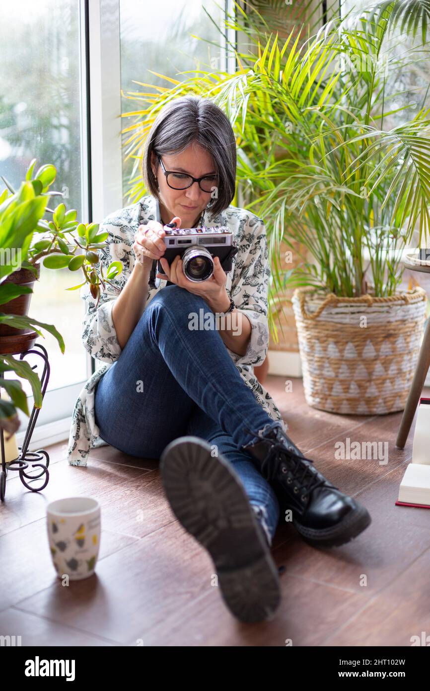 Erwachsene Frau, die eine Filmkamera aufsetzt. Sie ist auf der Terrasse ihres Hauses. Stockfoto