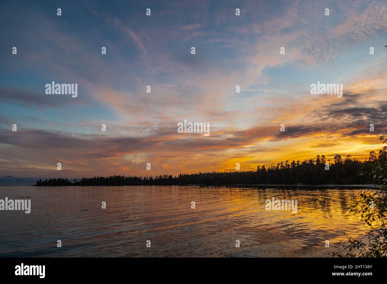 Eine Landschaft eines Sees, umgeben von einem Wald bei einem wunderschönen Sonnenaufgang am Morgen Stockfoto