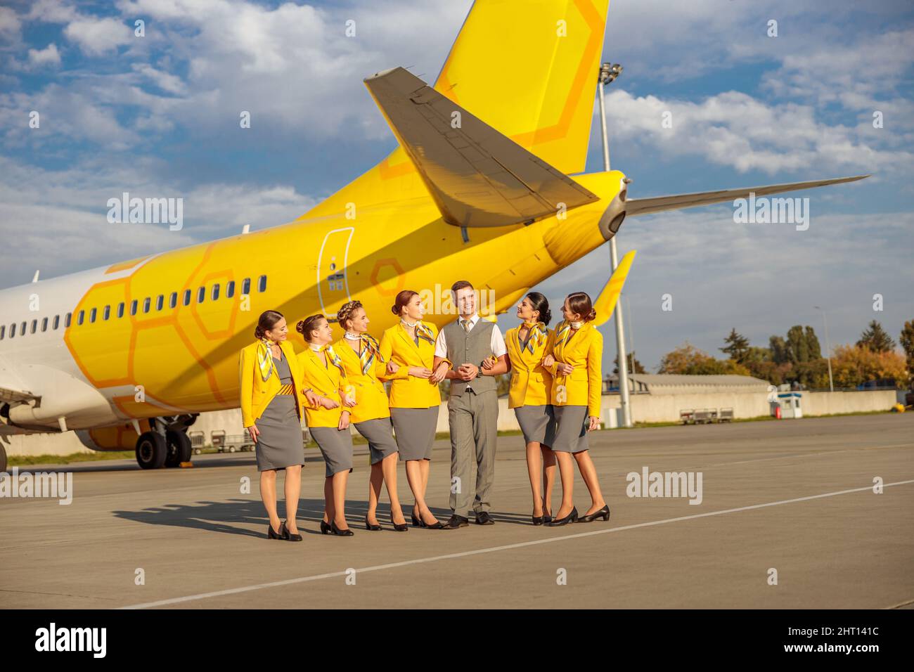 Mitarbeiter der Fluggesellschaft, die in der Nähe von gelben Flugzeugen auf dem Flugplatz stehen Stockfoto