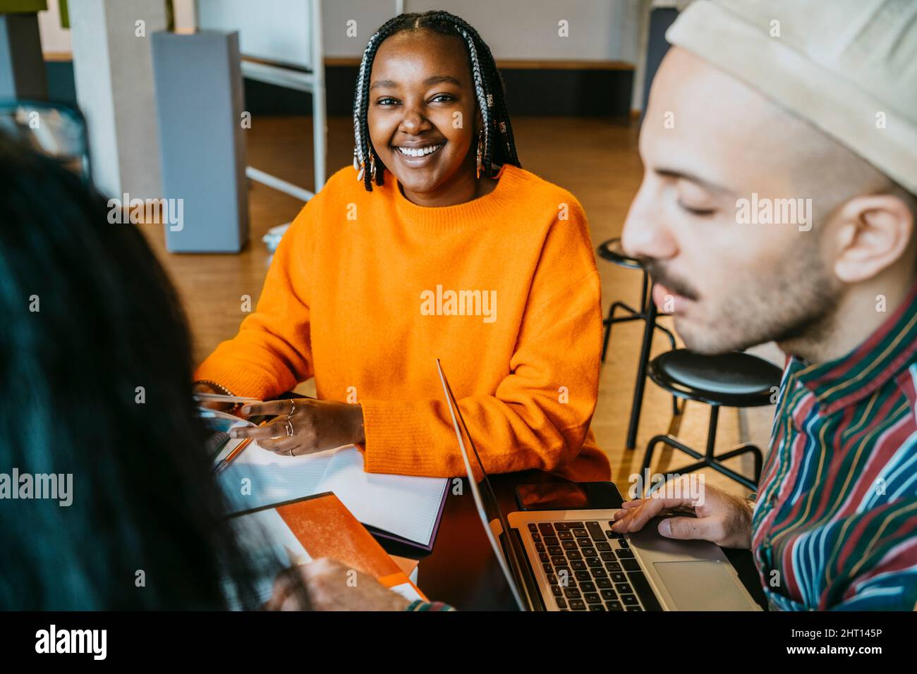 Porträt einer lächelnden jungen Frau, die von einem Freund in der Universitätskantine sitzt Stockfoto