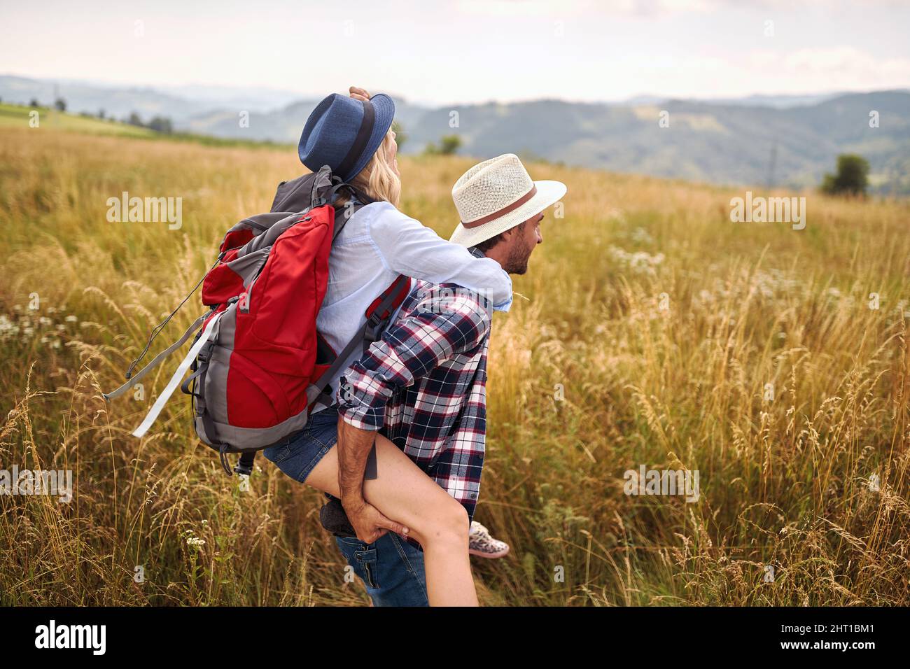 Ein junges, glückliches Paar in der Liebe hat Spaß, während er an einem schönen sonnigen Tag auf einer Wiese spazieren geht. Wandern, Natur, Beziehung, zusammen Stockfoto