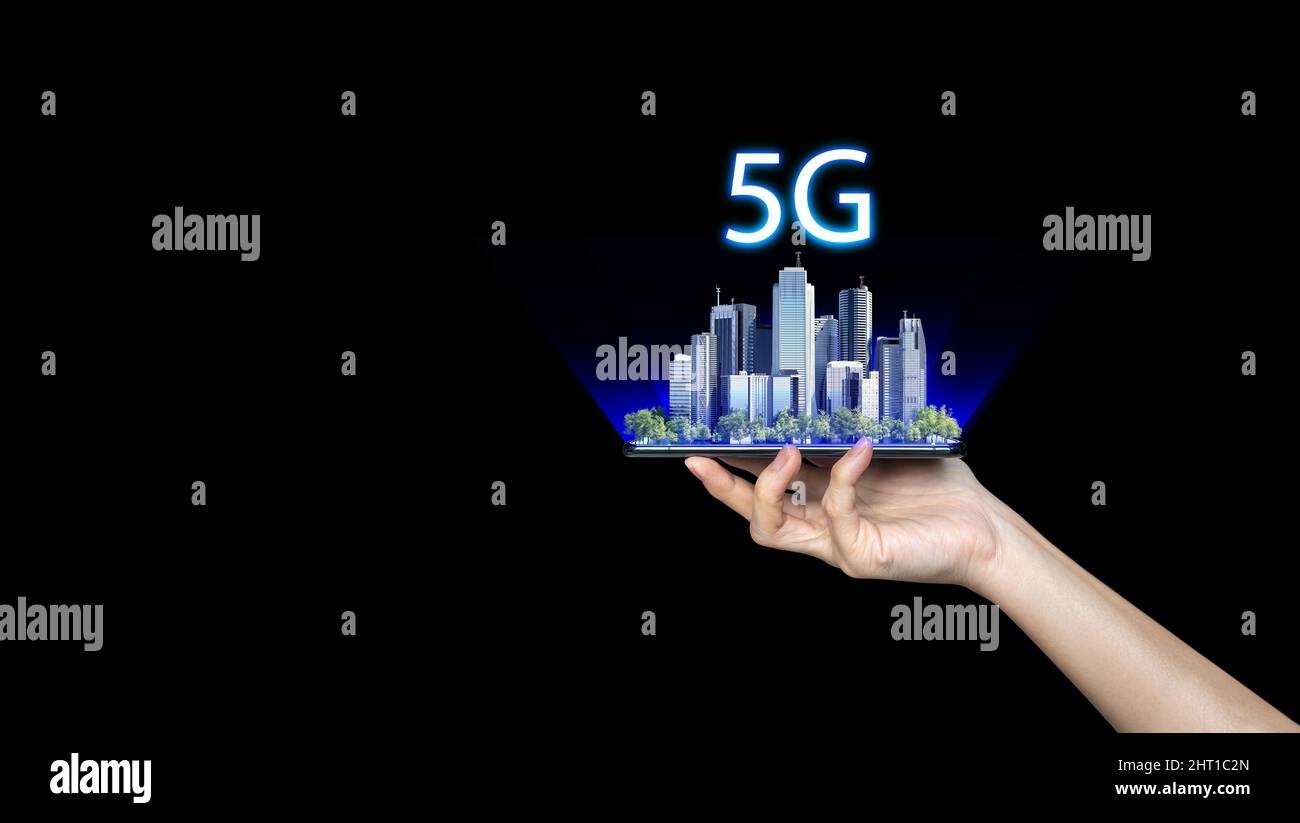 Hand hält ein Telefon mit einer 5G Smart City im Hintergrund. Das Konzept des 5G-Netzwerks, des mobilen Hochgeschwindigkeits-Internets und der Netzwerke der neuen Generation. Stockfoto