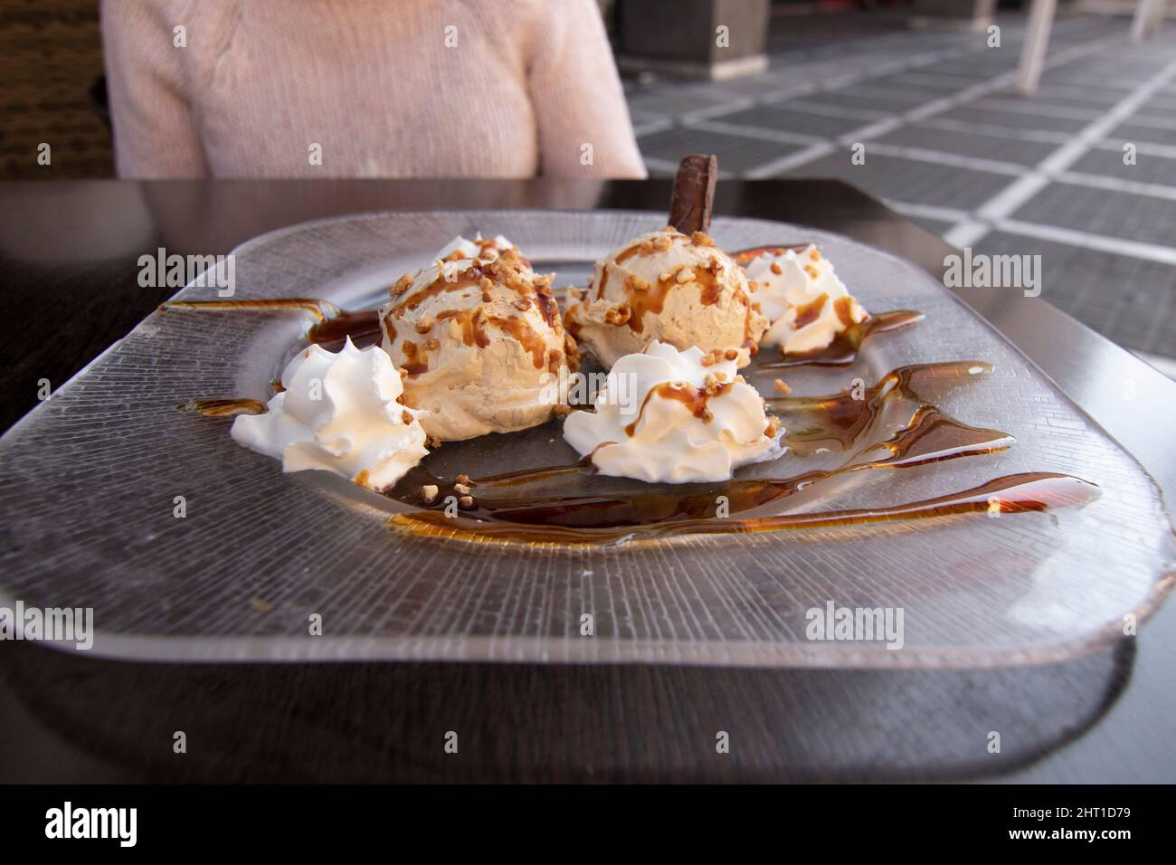 Ein sehr leckeres Dessert. Luis Felipe Mousse, Schokolade mit Creme und Karamell. Im Hintergrund eine unfokussierte Frau. Spanisches Speisekonzept. Stockfoto