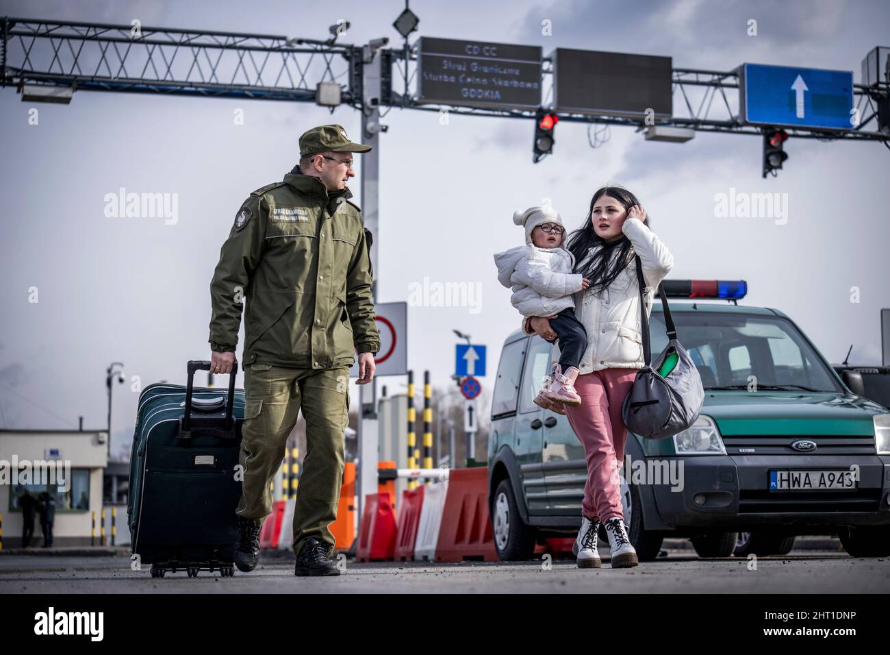 Przemysl, Polen. 26.. Februar 2022. Eine Grenzwache hilft einem Flüchtling aus der Ukraine mit ihrem Gepäck, nachdem sie die Grenze von Shehyni in der Ukraine nach Medyka in Polen überquert hat. Viele Ukrainer verlassen das Land nach militärischen Aktionen Russlands auf ukrainischem Territorium. Quelle: Michael Kappeler/dpa/Alamy Live News Stockfoto