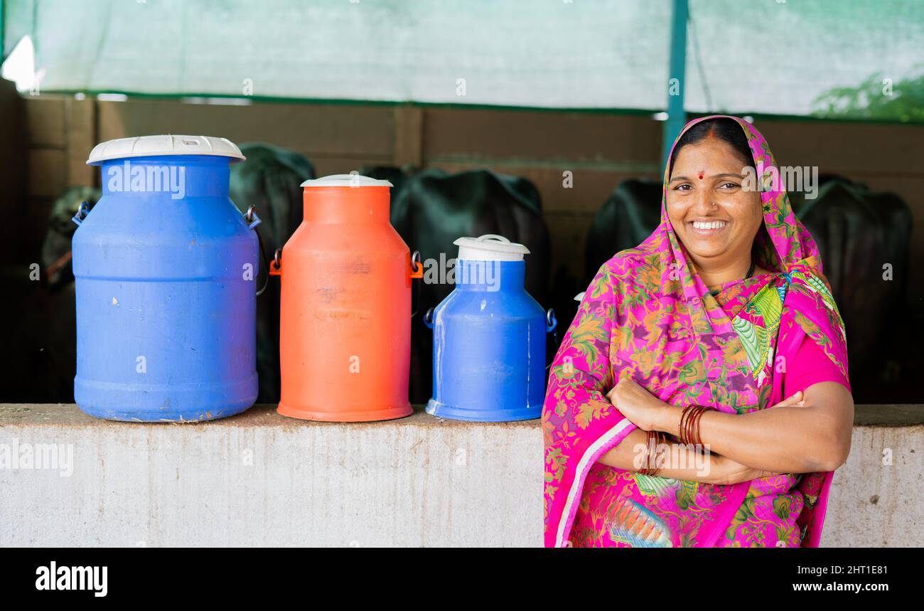 Portraitaufnahme einer glücklichen indischen Milchmilchfrau mit Milchbehältern und Rasseln hinter der Kamera - Konzept der Ermächtigung, Dorf Stockfoto