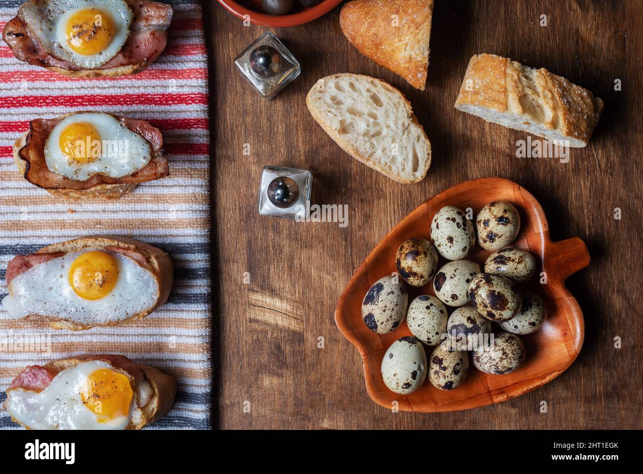 Scheibe Brot mit Speck und gegrilltem Wachtelei auf einem Holztisch. Stockfoto