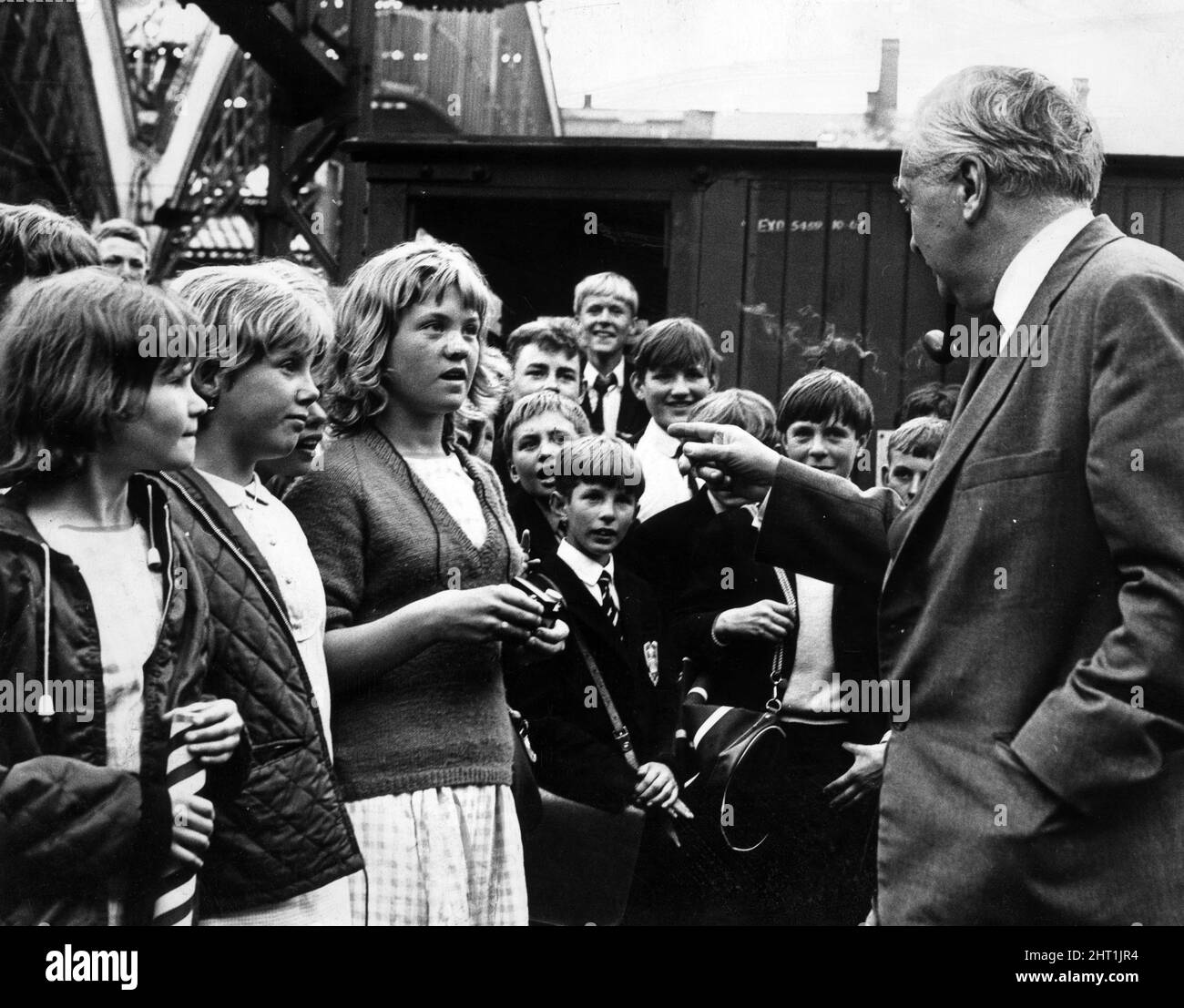 Premierminister Harold Wilson hält inne, um mit einer Gruppe von Kindern zu plaudern, die seinen Zug am Bahnhof Lime Street in Liverpool trafen. 2.. Juli 1966. Stockfoto