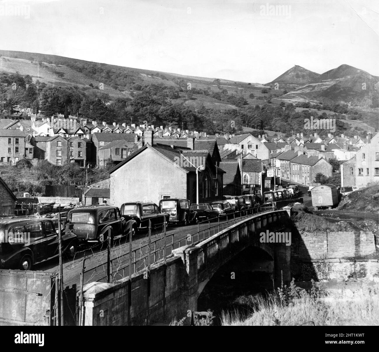 Aberfan - Erdrutsche - Katastrophen - Leichenwagen stehen über die Brücke zu einer der Kirchen, bevor sie die Särge zum Aberfan Friedhof bringen - 27. Okt 1966The Veranstaltungen am Freitag, den 21. Oktober 1966Tip no 7, das 500 Meter über dem Dorf Aberfan in der Nähe von Merthyr Tydfil lag, begann um 9,15 Uhr zu rutschen. Es war der letzte Tag vor der Halbzeit an den Pantglas-Schulen unten. Es traf zuerst eine Farm und tötete alle darin. Dann verschlang sie die Pantglas Junior School und tötete 109 Kinder und fünf Lehrer. Nur eine Handvoll der Kinder zwischen sieben und zehn Jahren überlebten. Die Spitze bestand aus Colliery Waste, Stockfoto