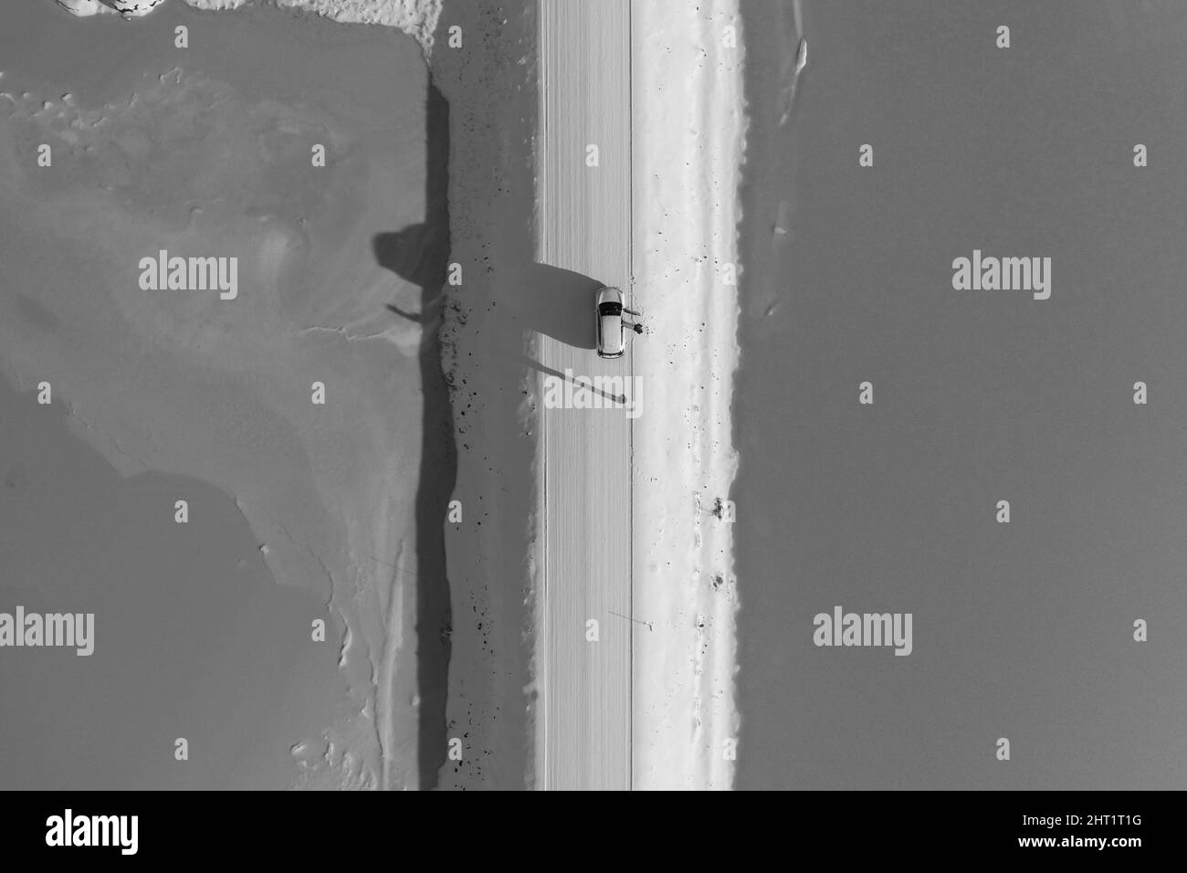 Graustufenansicht eines Autos, das auf einer geraden Straße in Island unterwegs ist Stockfoto