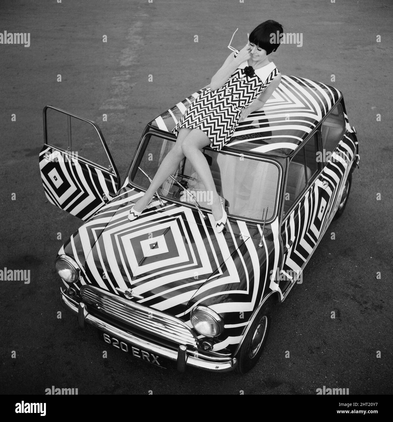 Hier ist es! Das Auto für das Mädchen Op Art (optisches Kunstmädchen), das alle ihre Accessoires passend mag, abgebildet am 24.. März 1966. Die Kunst wurde von der Amateurkünstlerin Danae Brook entworfen und angewendet, und das Auto steht in Thames Ditton, Surrey, zum Verkauf und kostet 385 £. Aber das beinhaltet nicht die Kosten für das Kleid, entworfen von Shubelle & das kostet 79 Schilling. Stockfoto