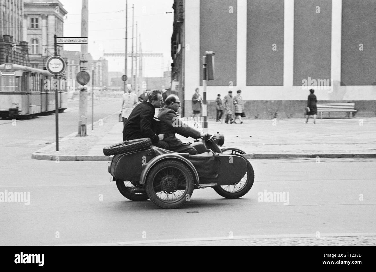 Szenen in Ost-Berlin, vier Jahre nach Beginn der Bauarbeiten an der Berliner Mauer, die Ost und West voneinander trennt.Ein Motorrad und ein Seitenwagen biegen in die Otto Grotewohl Straße ein (kürzlich umbenannt in Wilhelmstraße, nachdem sie durch die Berliner Mauer halbiert wurden). 26. Mai 1965. Stockfoto
