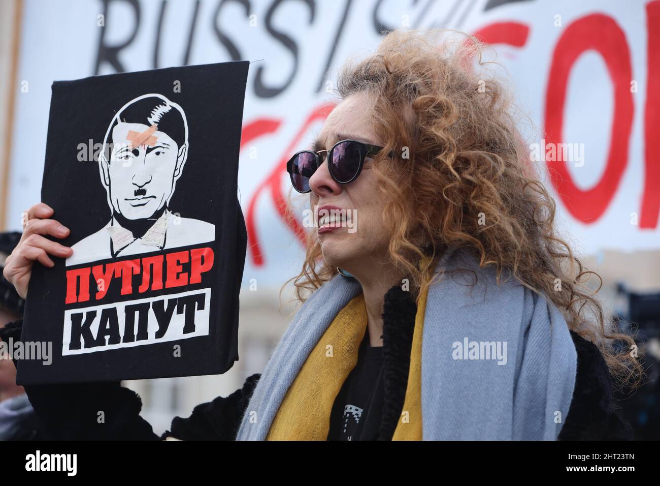 Magdeburg, Deutschland. 26.. Februar 2022. Ein Teilnehmer einer Kundgebung für den Frieden und gegen die russische Invasion in der Ukraine steht auf dem alten Markt und hält ein Schild mit einem Bild eines Gesichts, das eine Mischung aus Hitler und Putin ist. Quelle: Matthias Bein/dpa-Zentralbild/dpa/Alamy Live News Stockfoto