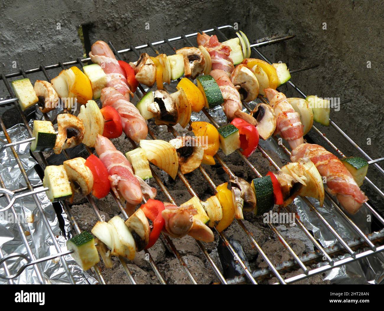 Gegrillte Spieße mit Wurst, Speck und Gemüse Stockfoto