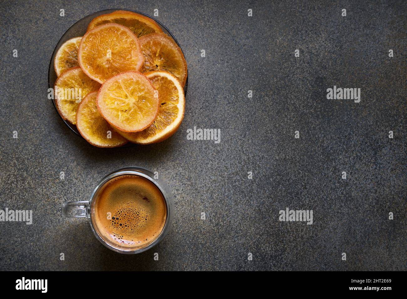 Doppelter Espresso-Kaffeetasse und -Teller aus Glas mit getrockneten orangefarbenen Scheiben, Draufsicht, Platz für Text Stockfoto