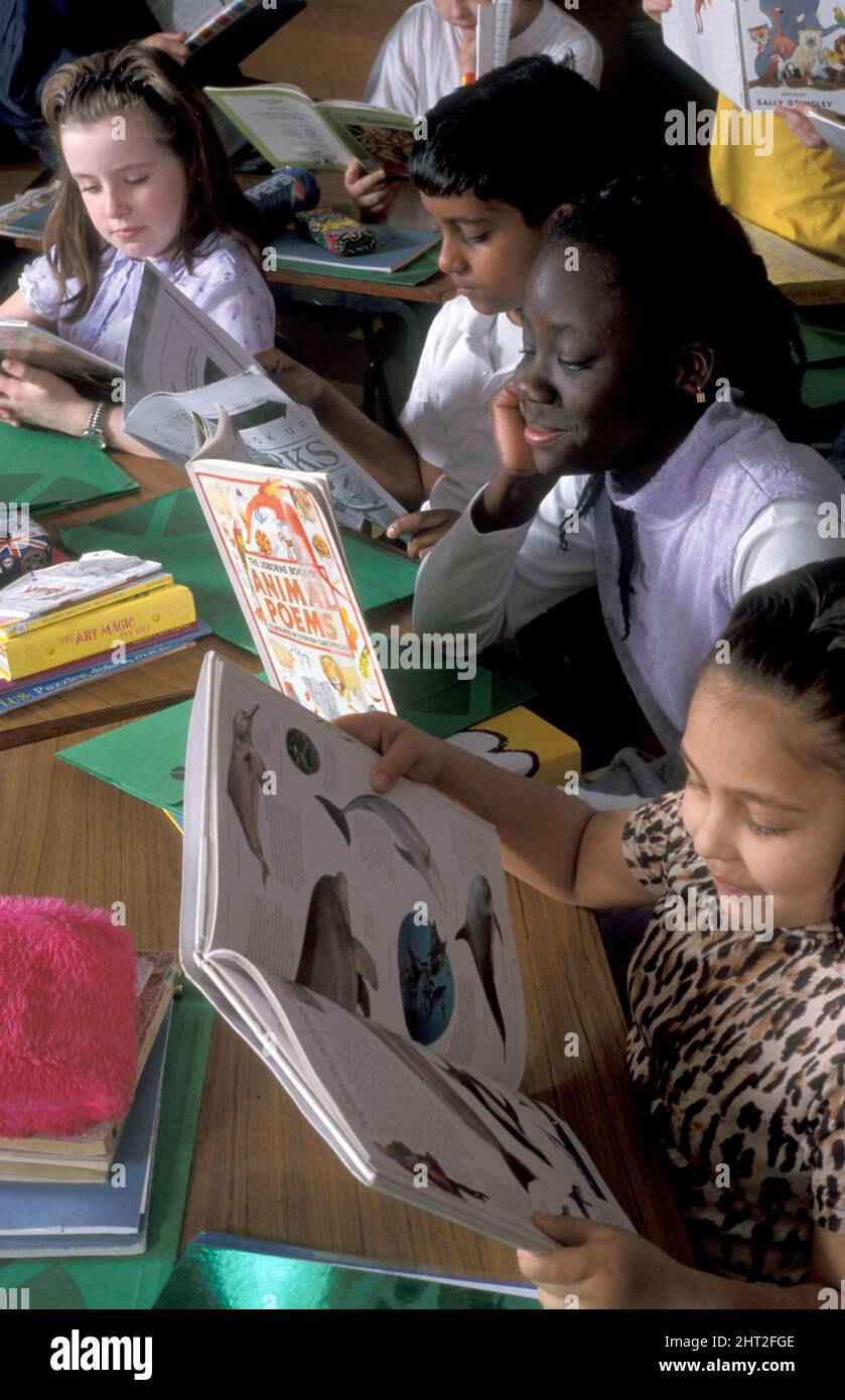 Gruppe multikultureller Kinder, die im Klassenzimmer lesen Stockfoto