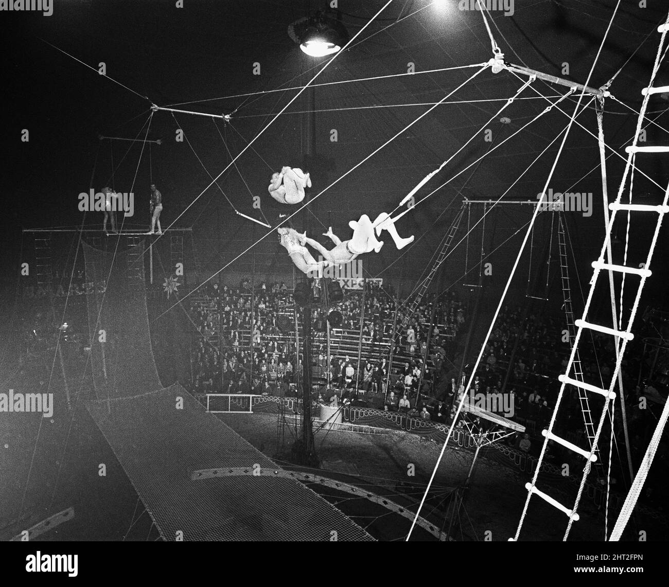 Hoch oben, 60 Meter über einem stillen Publikum in Billy Smart's Circus Hay Mills, Birmingham, West Midlands, spielen die Flying Ibarras ihren atemberaubenden Split Second Act, "The Double Passage". 27.. März 1965 Stockfoto