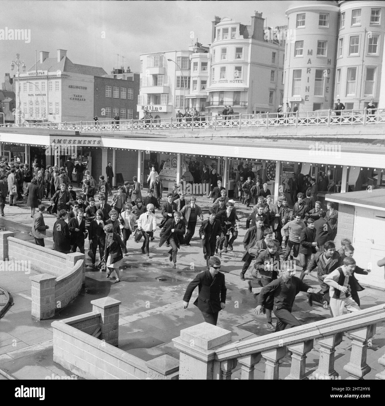 Die Mods und Rockers waren zwei widersprüchliche britische Jugendsubkulturen von Anfang bis Mitte 1960s. Die Berichterstattung über die Kämpfe von Mods und Rockern im Jahr 1964 löste eine moralische Panik über britische Jugendliche aus, und die beiden Gruppen wurden als Volksteufel bezeichnet. Mods laufen unter der Promenade von Brighton. 18.. April 1965. Stockfoto
