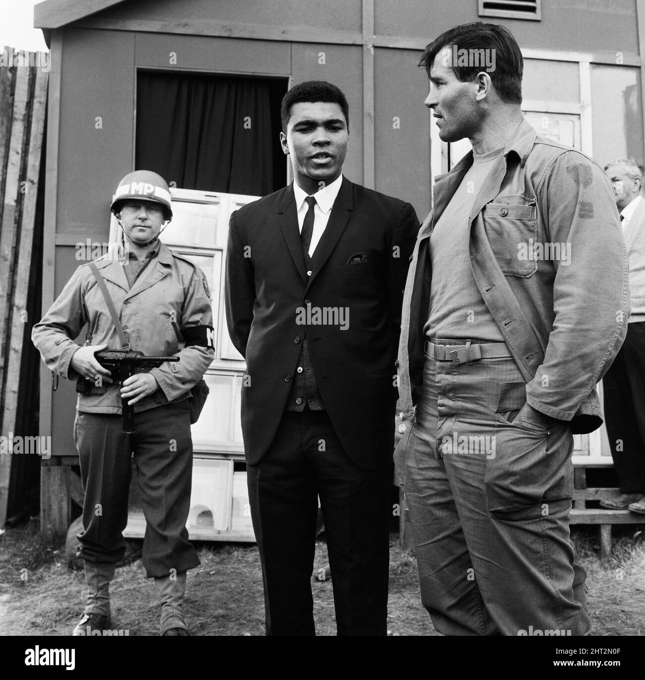 Muhammad Ali (Cassius Clay) hat sich vor seinem bevorstehenden Titelkampf mit Brian London ausruhen lassen. Clay besuchte den Film, der in der Beechwood Park School, Markyate, Hertfordshire, gedreht wurde, wo MGN Sequenzen von "The Dirty Dozen" filmte. (Bild) Muhammad Ali und Clint Walker G.I . ein Gespräch unter dem, was aussieht wie bewaffnete Wächter. 6.. August 1966 Stockfoto