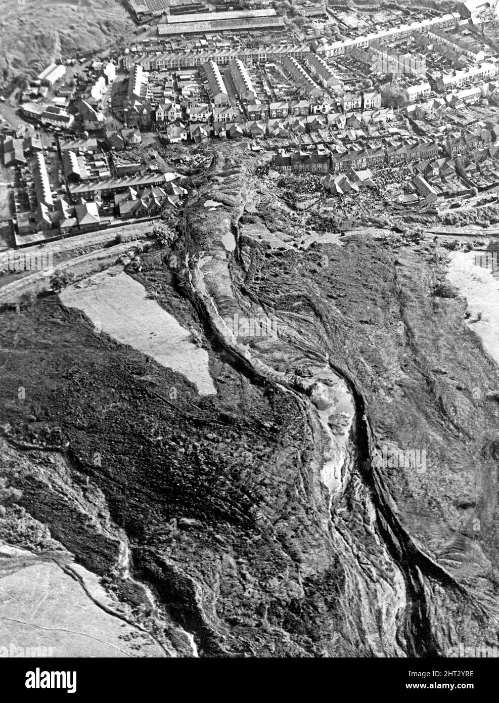 Aberfan, Südwales. Bild aufgenommen 1pm am 21.. Oktober 1966. Das aus der Luft aufgenommene Bild zeigt die Bergspitze und den Minenraub, der den Hang hinunter gerutscht hat und die Schule und einen Teil der Stadt zerstört hat. Die Katastrophe von Aberfan war ein katastrophaler Einsturz einer kollidierenden Beute im walisischen Dorf Aberfan, in der Nähe von Merthyr Tydfil, am Freitag, dem 21.. Oktober 1966. Er wurde durch eine Ansammlung von Wasser im angesammelten Fels und Schiefer verursacht, die plötzlich in Form von Schlamm bergab zu rutschen begann und am 21.. Oktober 1966 die Pantglas Junior School darunter verschlang und 116 Kinder tötete Stockfoto