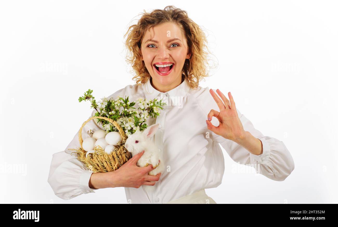 Frohe Ostern. Lächelnde Frau mit einem Zeichen. Eiersuche. Fröhliches Mädchen mit Körbchen und kleinem Hasen. Stockfoto