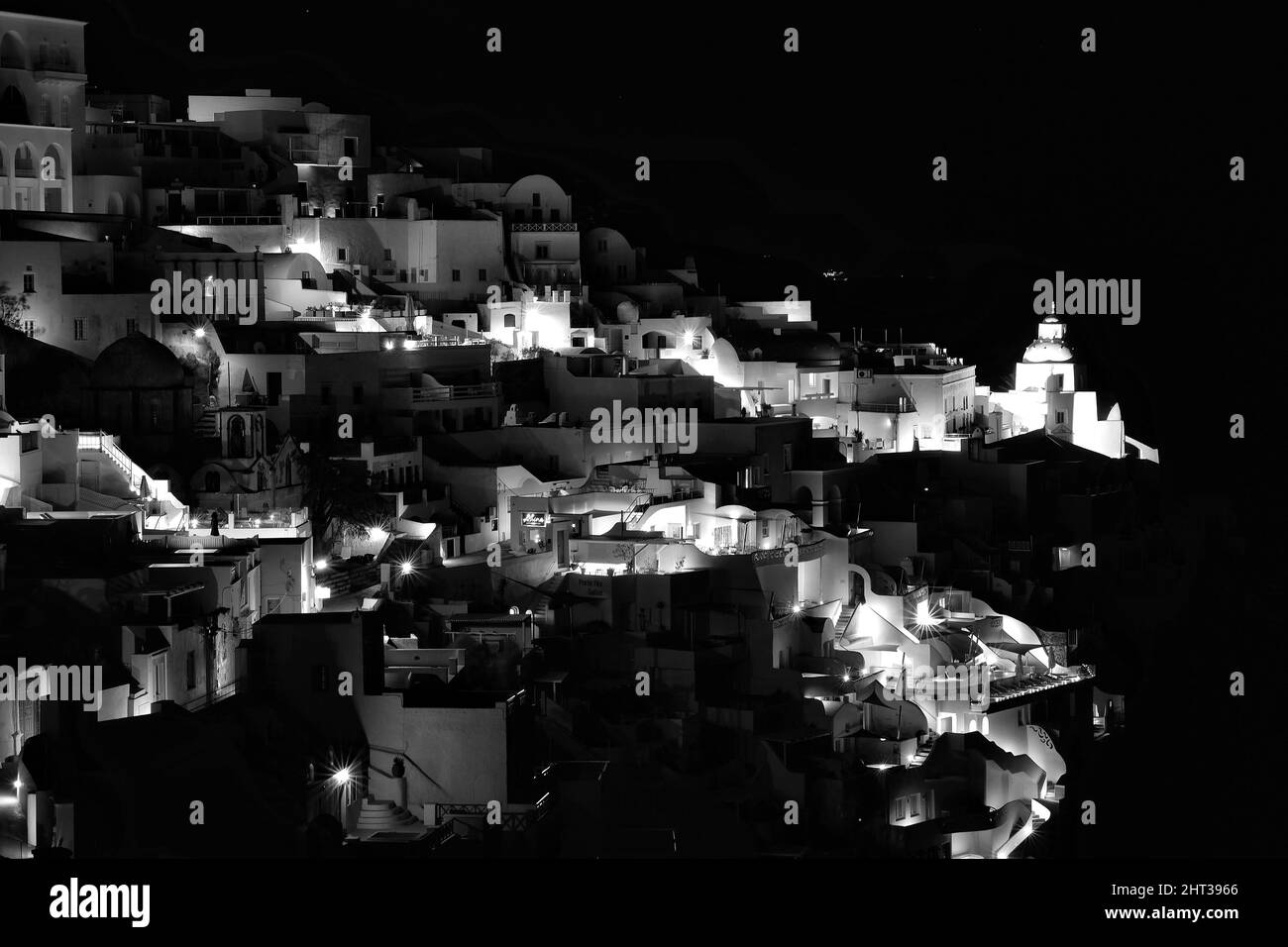 Panoramablick auf das malerische beleuchtete Dorf Fira Santorini Griechenland bei Nacht in schwarz-weiß Stockfoto