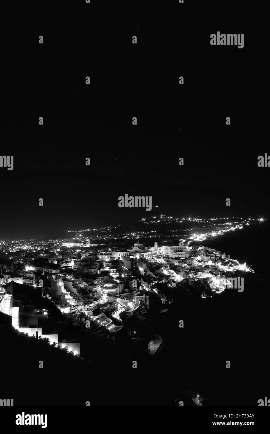 Panoramablick auf das malerische beleuchtete Dorf Fira Santorini Griechenland bei Nacht in schwarz-weiß Stockfoto