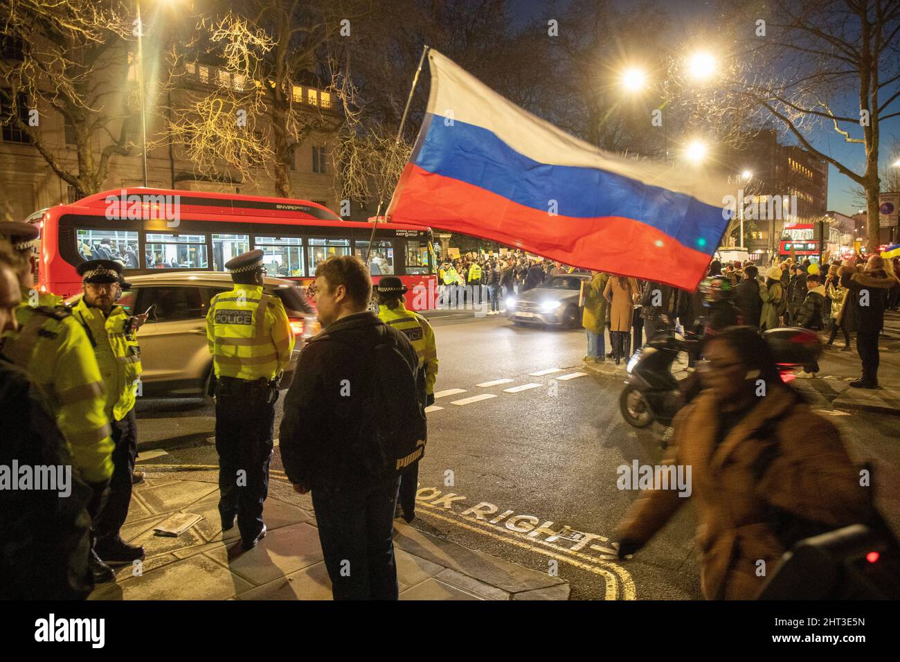LONDON, FEBRUAR 26 2022 Pro-russischer Protestler mit russischer Flagge als Pro-ukrainische Demonstranten vor der russischen Botschaft gegen die russische Invasion in der Ukraine protestieren Stockfoto