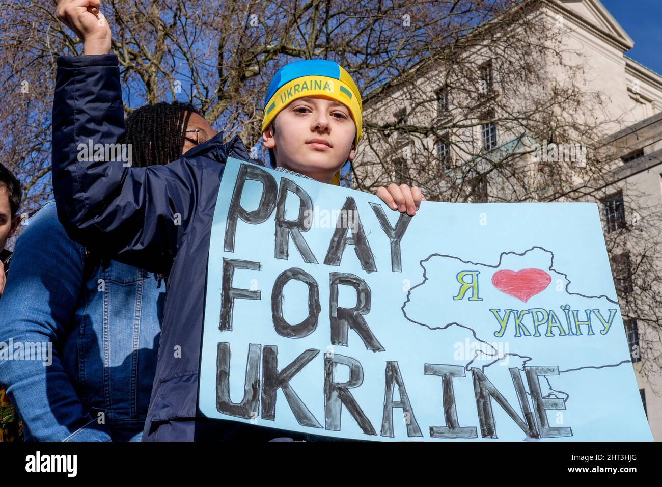 26.. Februar 2022: Ukrainische Staatsbürger und pro-ukrainische Anhänger versammeln sich in Whitehall, um gegen die russische Invasion in der Ukraine zu protestieren. London, Großbritannien. Im Bild: Ein kleiner Junge steht über der Menge und hält ein Plakat für Gebete für die Ukraine. Stockfoto