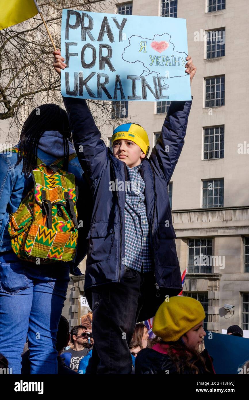 26.. Februar 2022: Ukrainische Staatsbürger und pro-ukrainische Anhänger versammeln sich in Whitehall, um gegen die russische Invasion in der Ukraine zu protestieren. London, Großbritannien. Im Bild: Ein kleiner Junge steht über der Menge und hält ein Plakat für Gebete für die Ukraine. Stockfoto