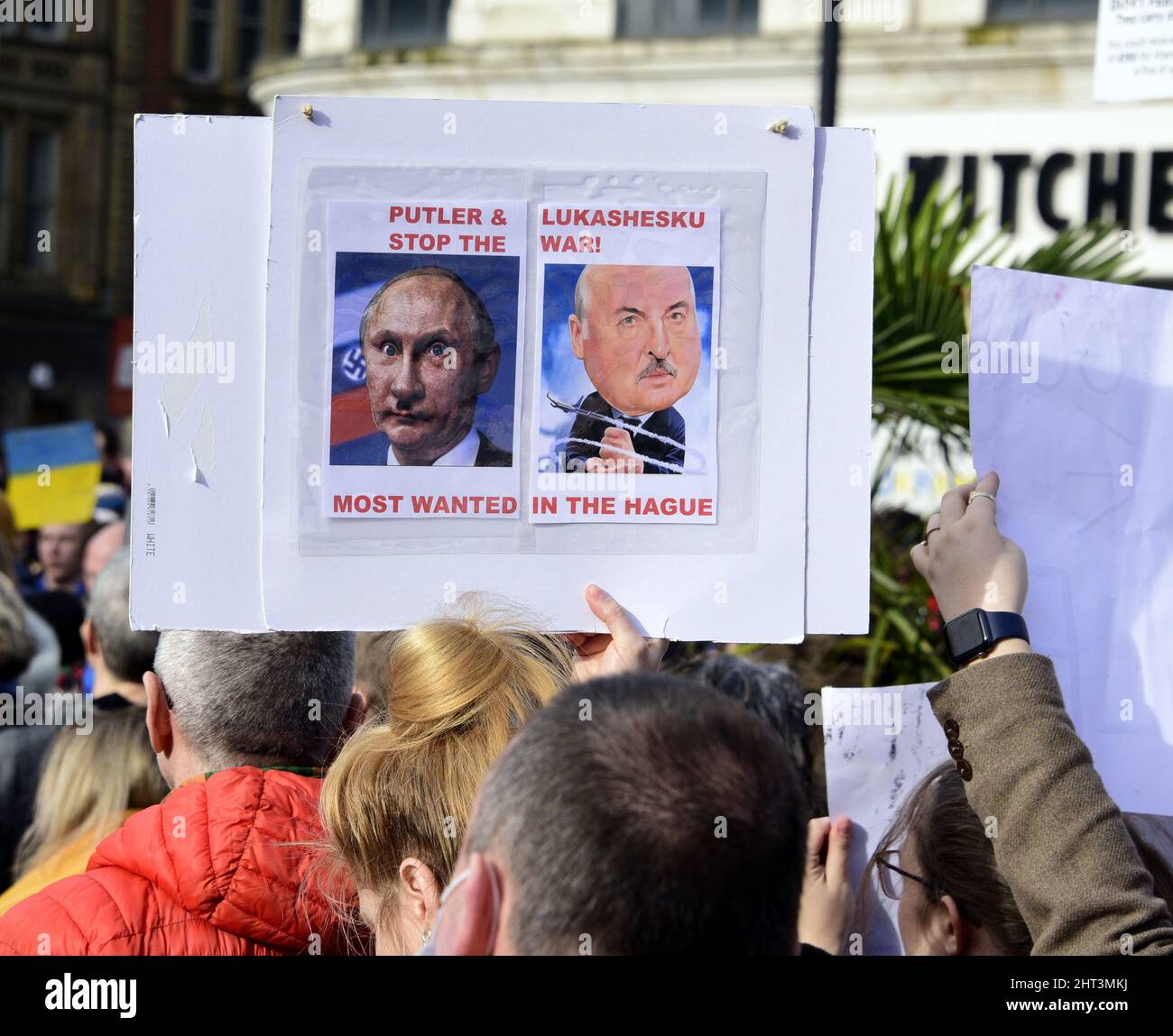 Manchester, Großbritannien, 26.. Februar 2022. Plakate beziehen sich auf Putler als neuen Namen für Putin, der auf eine Ähnlichkeit mit Hitler verweist. Das Plakat deutet darauf hin, dass Alexander Lukaschenko, Präsident von Belarus, mit Putin in Den Haag als Kriegsverbrecher vor Gericht gestellt werden sollte. Hunderte von Menschen protestierten neben der Statue der Königin Victoria in Piccadilly Gardens, im Zentrum von Manchester, England, Großbritannien, gegen die russische Invasion in der Ukraine. Es wurde vom Ukrainischen Kulturzentrum „Dnipro“ Manchester organisiert. Quelle: Terry Waller/Alamy Live News Stockfoto