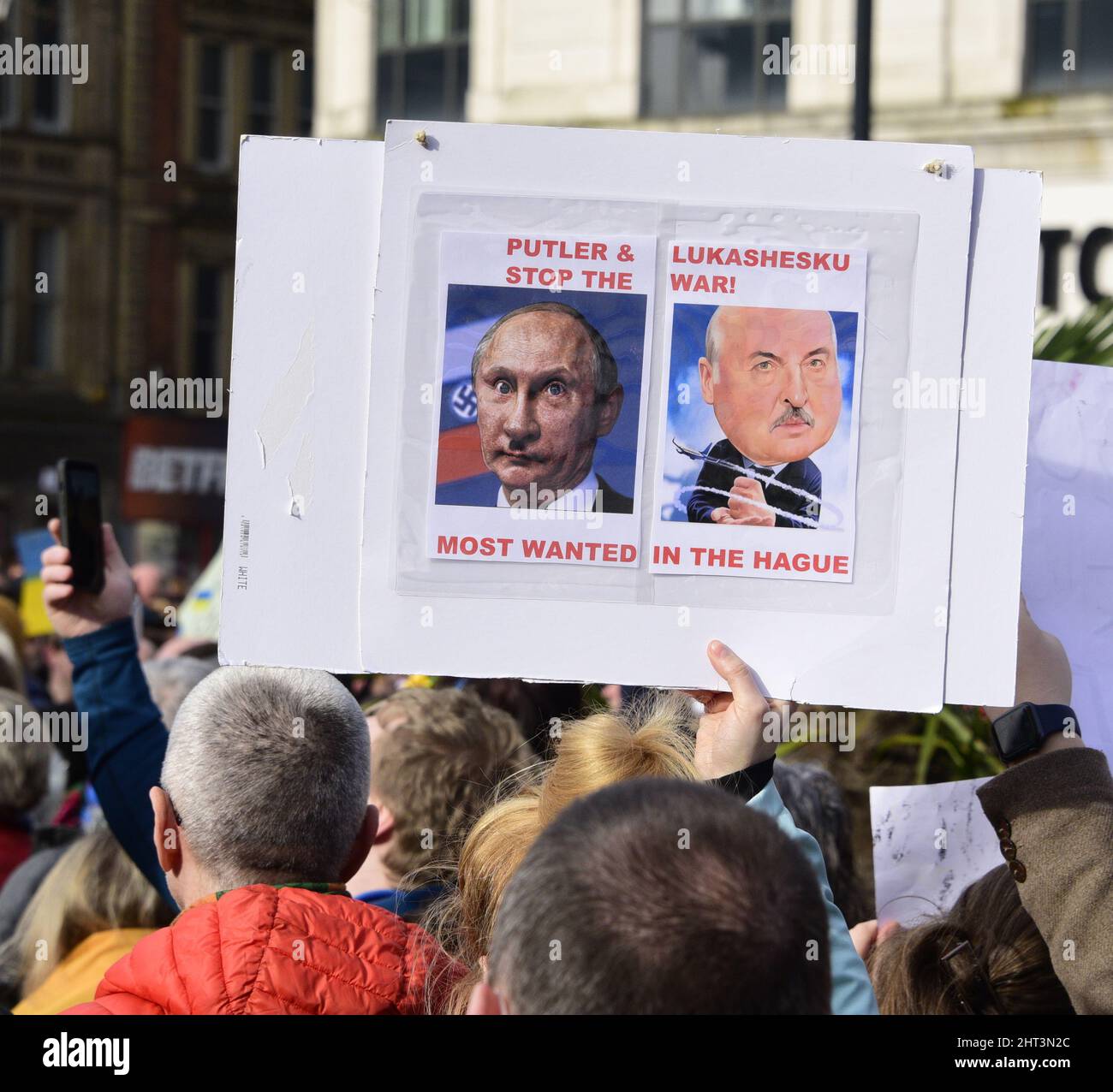 Manchester, Großbritannien, 26.. Februar 2022. Plakate beziehen sich auf Putler als neuen Namen für Putin, der auf eine Ähnlichkeit mit Hitler verweist. Das Plakat deutet darauf hin, dass Alexander Lukaschenko, Präsident von Belarus, mit Putin in Den Haag als Kriegsverbrecher vor Gericht gestellt werden sollte. Hunderte von Menschen protestierten neben der Statue der Königin Victoria in Piccadilly Gardens, im Zentrum von Manchester, England, Großbritannien, gegen die russische Invasion in der Ukraine. Es wurde vom Ukrainischen Kulturzentrum „Dnipro“ Manchester organisiert. Quelle: Terry Waller/Alamy Live News Stockfoto