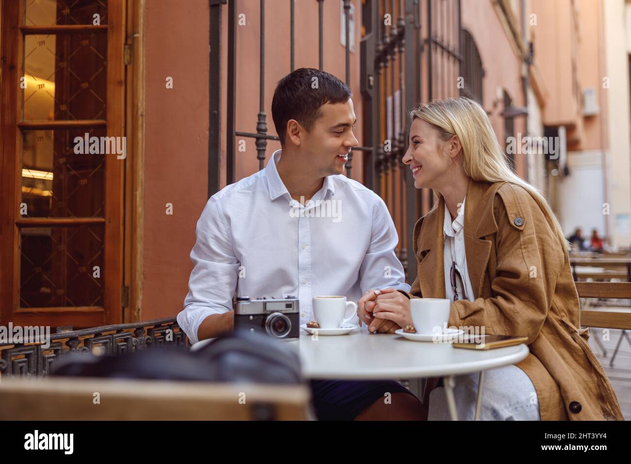 Porträt eines hübschen Paares, das im Café von Außenbeinen sitzt und spricht Stockfoto