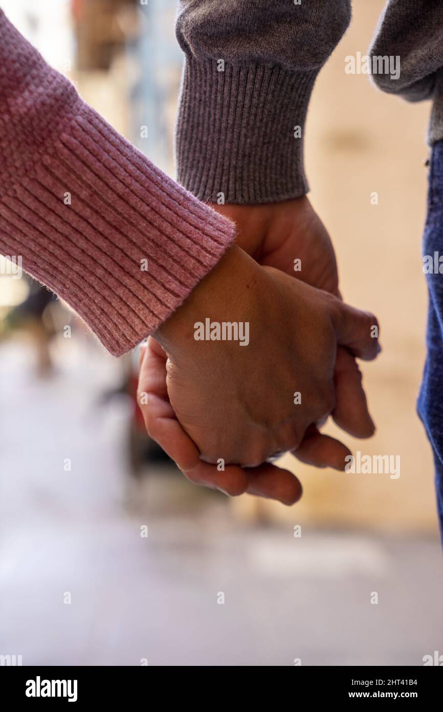 Vertikale Nahaufnahme eines jungen Paares, das die Hände hält Stockfoto