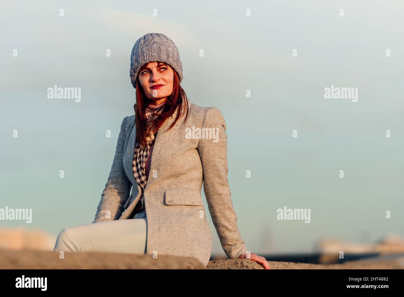 Frau, die auf einer Steinmauer sitzt und die Sonne beobachtet Stockfoto