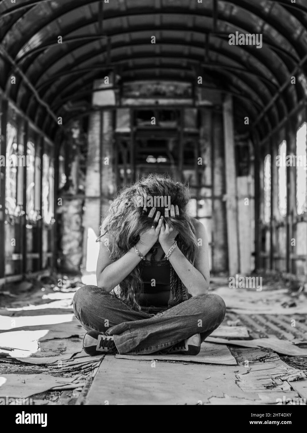 Eine vertikale Aufnahme einer traurigen Frau in einem verlassenen Zug Stockfoto
