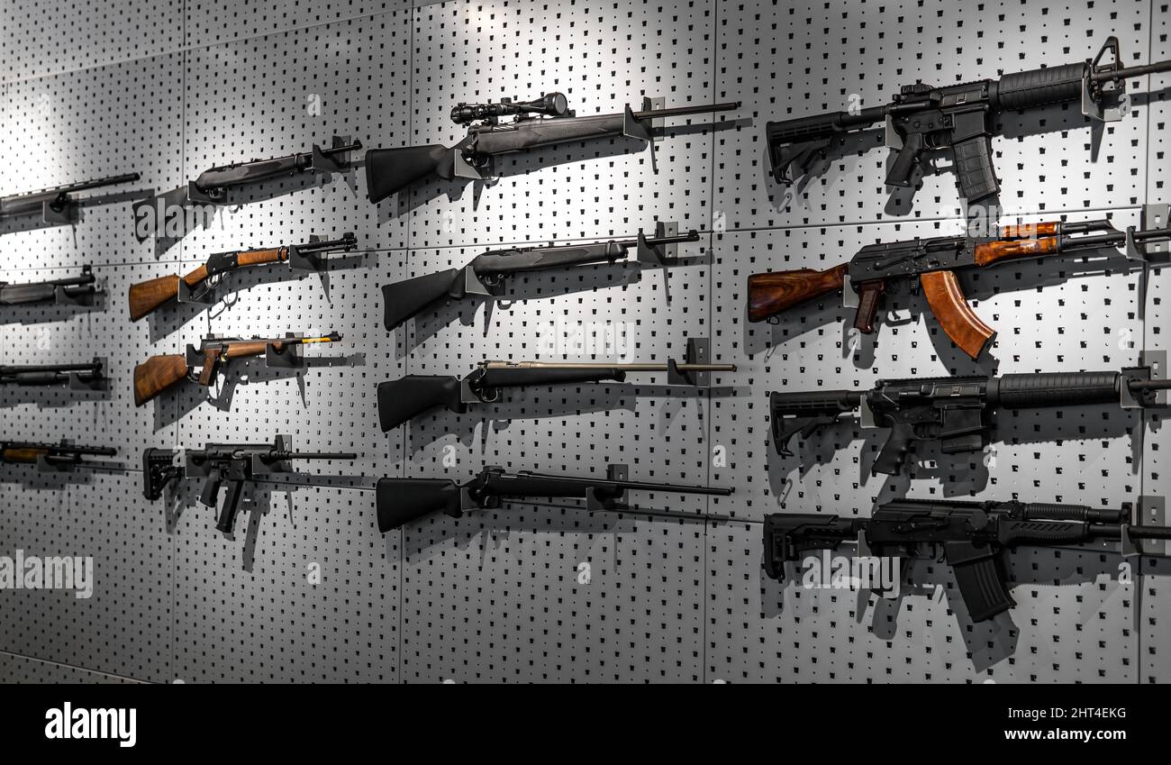 Sammlung von Gewehren und Karabinen. Verschiedene Schusswaffen hängen an speziellen Halterungen an der Wand. Waffenhintergrund. Stockfoto