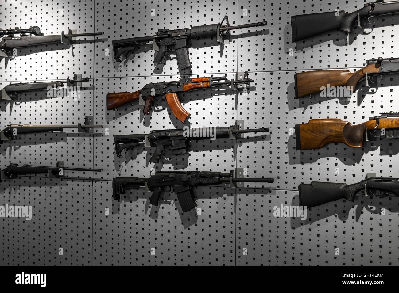 Sammlung von Gewehren und Karabinen. Verschiedene Schusswaffen hängen an speziellen Halterungen an der Wand. Waffenhintergrund. Stockfoto