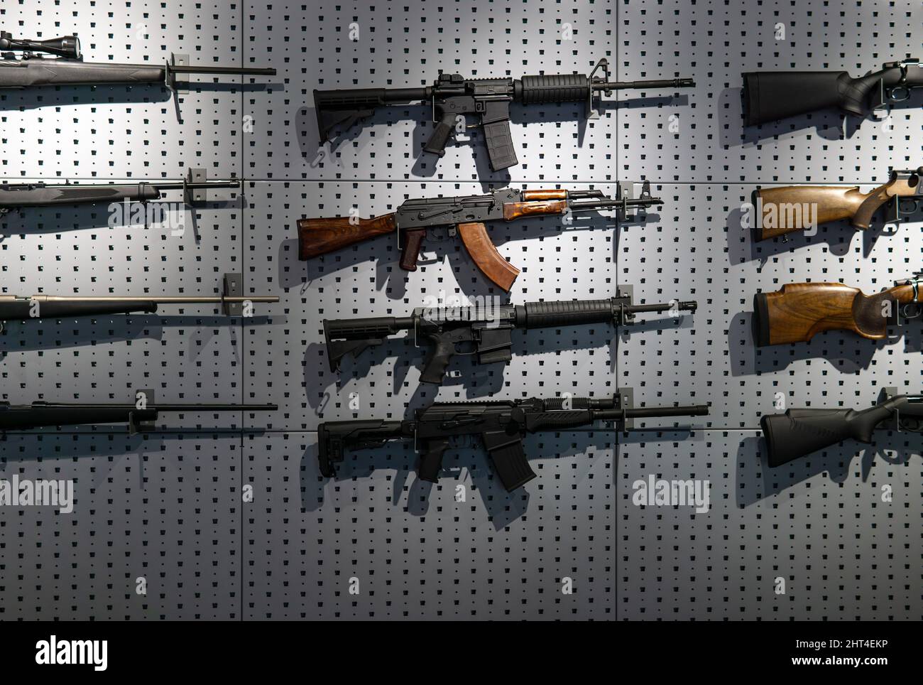 Sammlung von Gewehren und Karabinen. Verschiedene Schusswaffen hängen an speziellen Halterungen an der Wand. Waffenhintergrund. Stockfoto