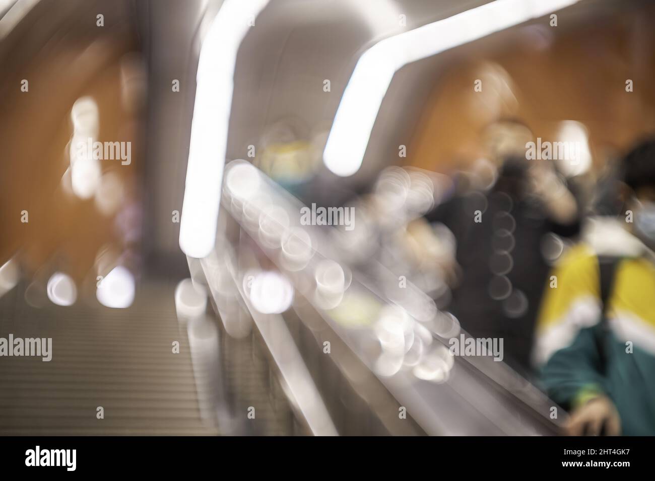 Helle Bokeh-Lichter im unscharfen Bild von Menschen auf der unterirdischen Rolltreppe Stockfoto