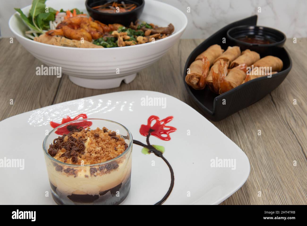 Herzhafte vietnamesische gekochte 3-Gänge-Mahlzeit, bestehend aus Vermicelli-Salat, Shrimp-Brötchen und coppa Mascarpone als Dessert. Stockfoto