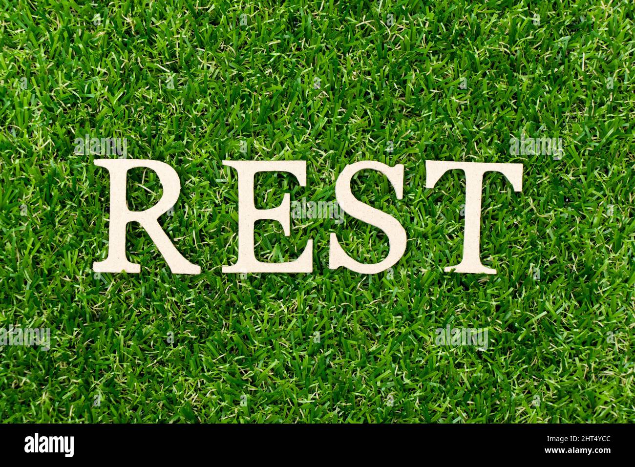 Holzbuchstabe in Wort Rest auf grünem Gras Hintergrund Stockfoto
