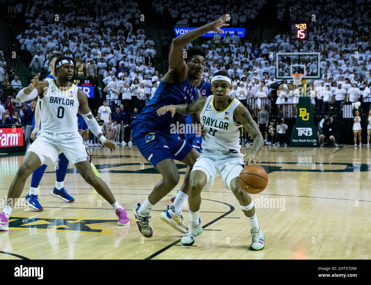 Waco, Texas, USA. 26.. Februar 2022. Baylor Bears Wache James Akinjo (11) fährt mit dem Ball gegen Kansas Jayhawks Stürmer David McCormack (33) während der 2. Hälfte des NCAA Männer Basketballspiels zwischen den Kansas Jayhawks und Baylor Bears im Ferrell Center in Waco, Texas. Matthew Lynch/CSM/Alamy Live News Stockfoto